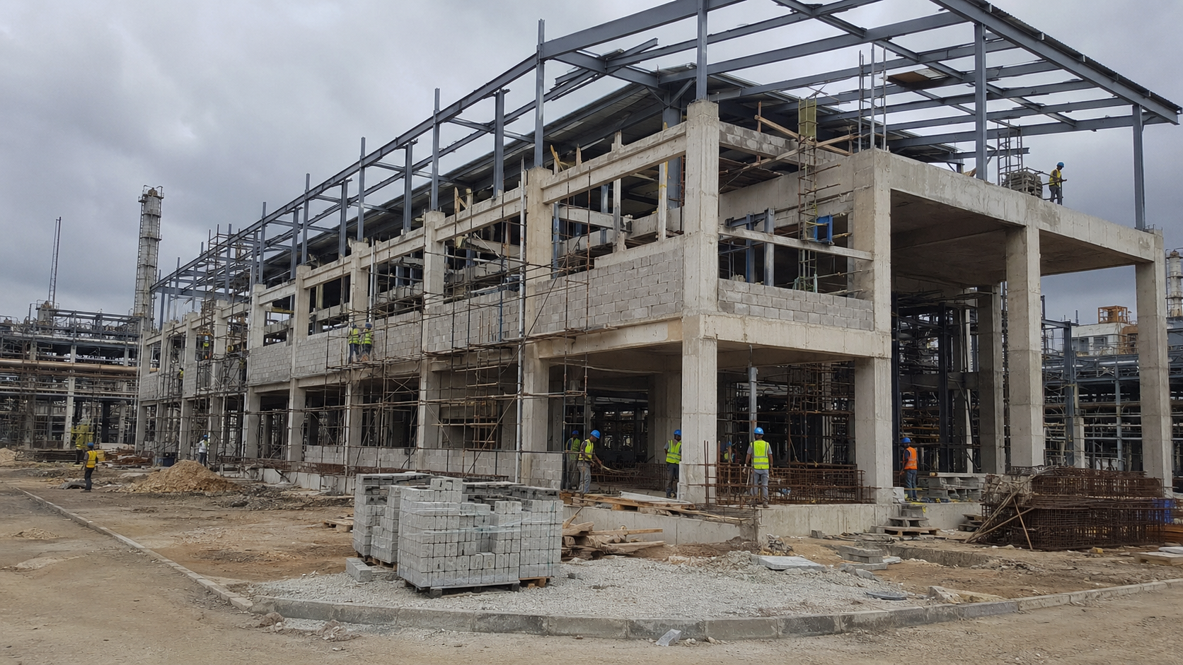 Large industrial building under construction with concrete frame and steel roof