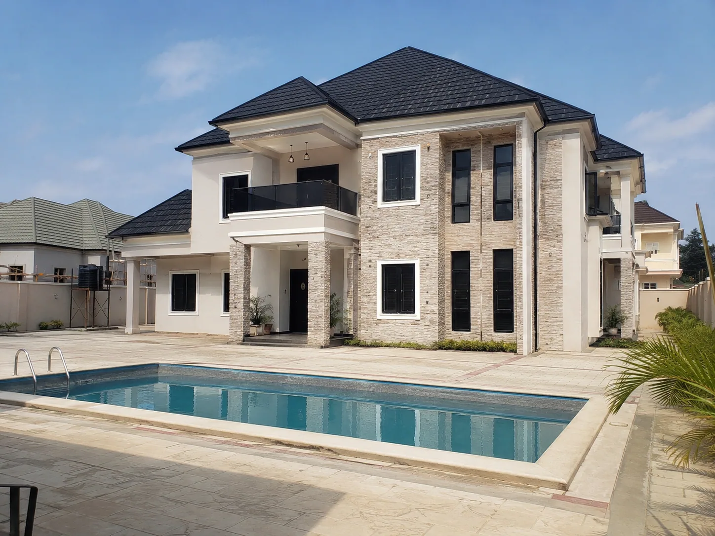 Completed residence with a prominent rectangular swimming pool and paved deck