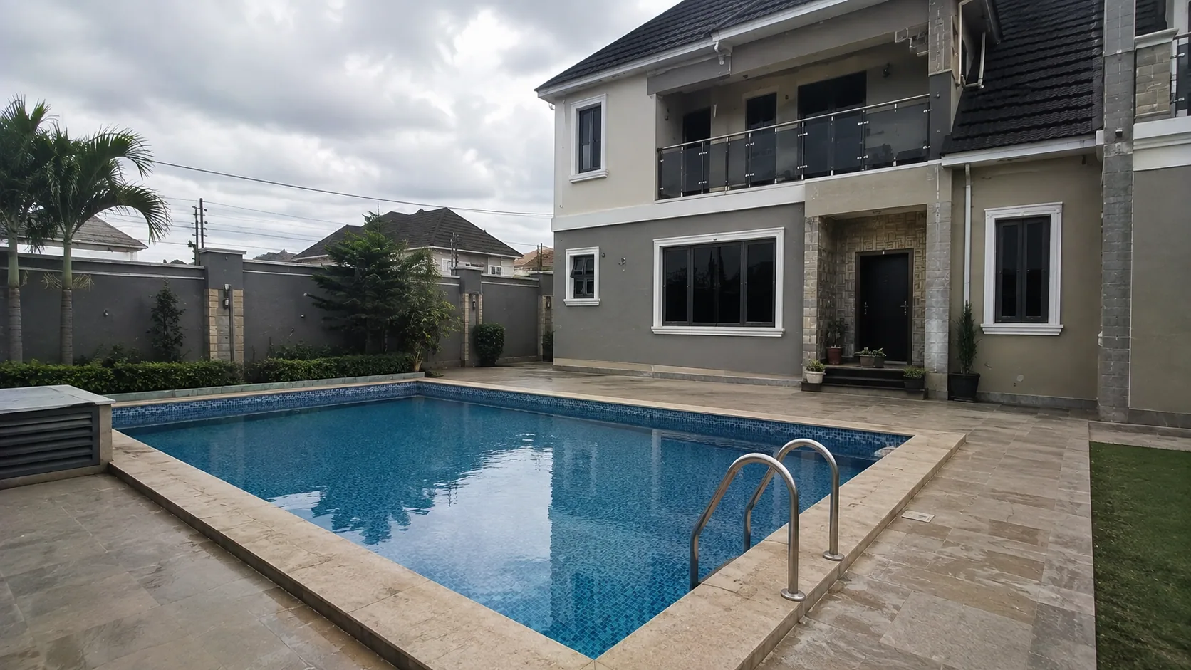 Completed rectangular tiled swimming pool beside a two-storey residence